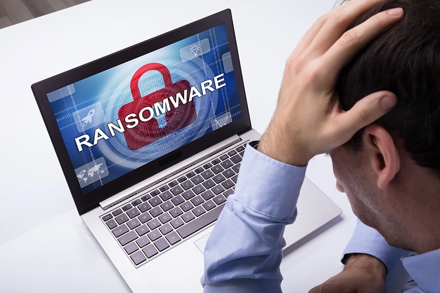 Worried Businessman Looking At Laptop With Ransomware Word On The Screen At The Workplace